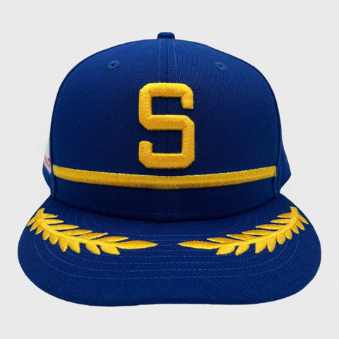 Blue fitted hat with yellow 'S' and leaf designs on a light gray background
