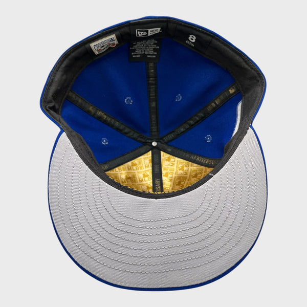 Baseball cap with blue interior, black rim, and gold and white pattern on the brim against a light gray background.