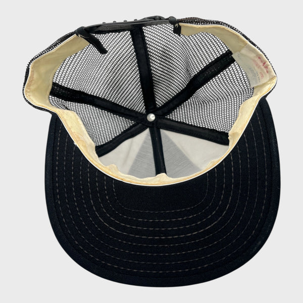 Underside of a black mesh trucker hat on a light gray background