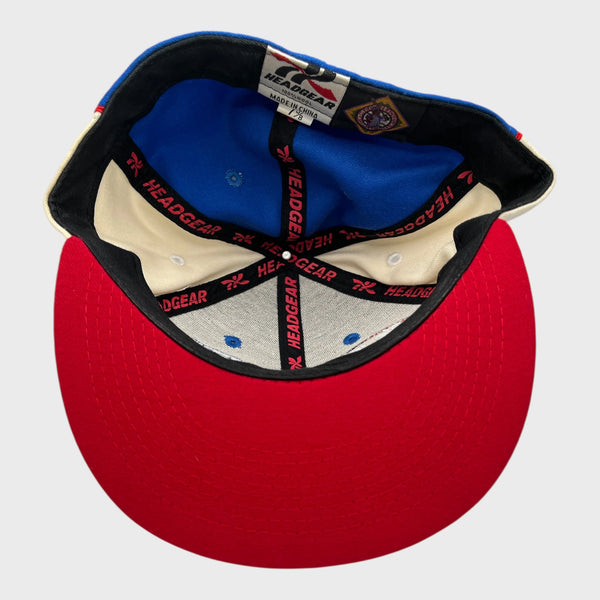 Underside of a red and blue fitted baseball cap with visible branding on a white background