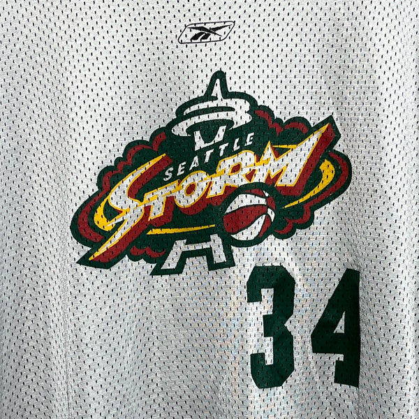 Close-up of a white basketball jersey with 'Seattle Storm' logo and number '34'.