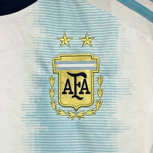 Close-up of a sports jersey with an embroidered AFA logo on a light blue and white striped background.