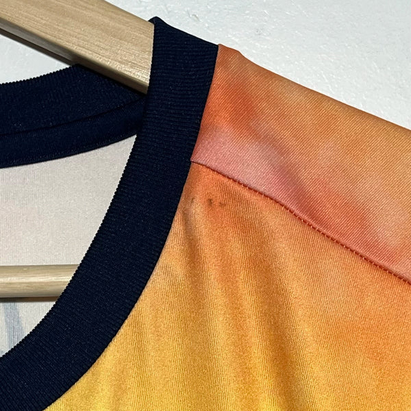 Close-up of a garment with black and orange fabric on a wooden hanger against a white background